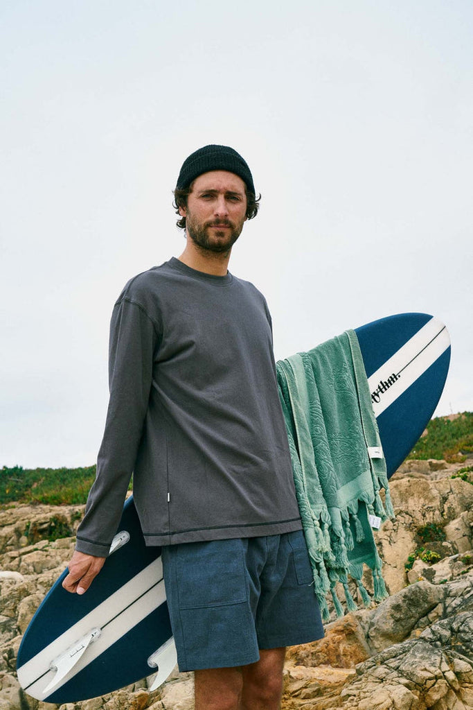 Man wearing Rhythm Longsleeve Tshirt while holding a surfboard