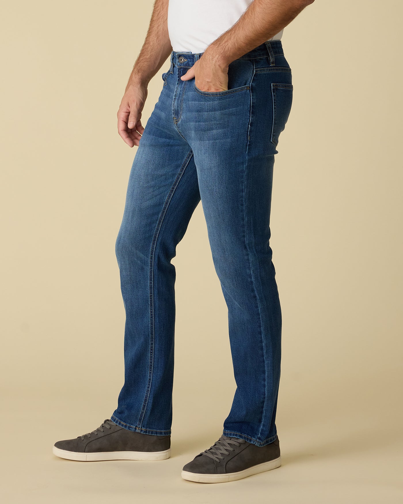 Person wearing blue jeans on a beige background